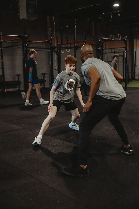 A young athlete practices defensive agility drills with a coach during a 1-on-1 sports performance training session at Lumen Athletics in Cheyenne, WY.
