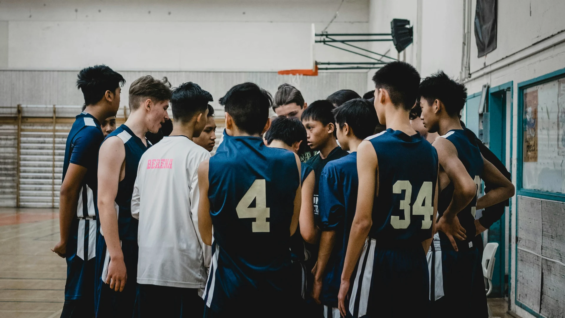Teen basketball team huddled together in a gym before a game, representing youth sports performance training at Lumen Athletics in Cheyenne, WY.