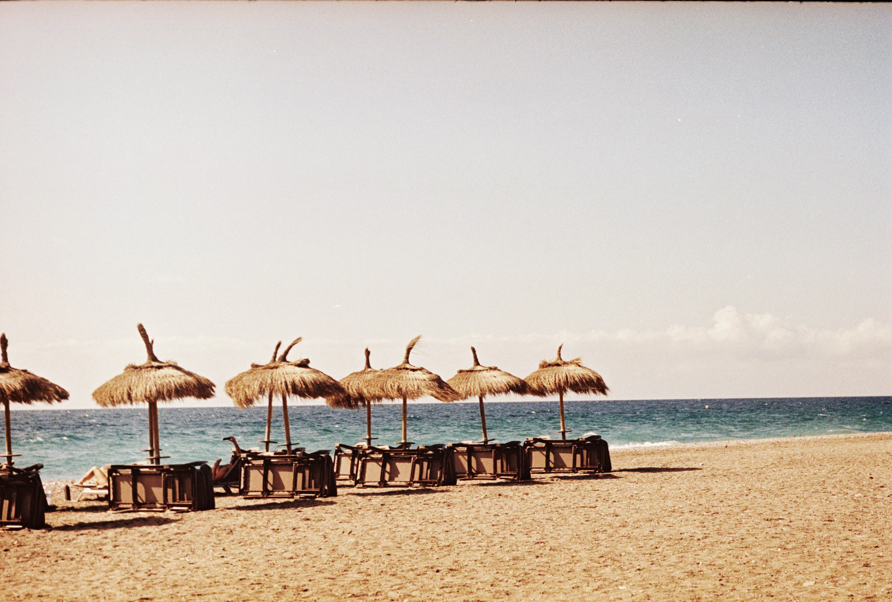 Beach lined with thatched parasols by the sea