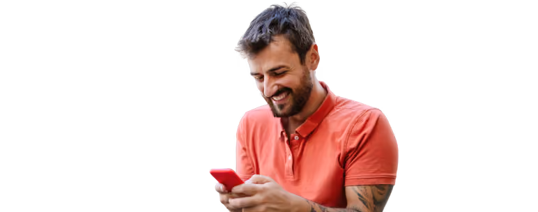 Hombre con camisa roja sonriendo mientras usa un teléfono celular rojo.