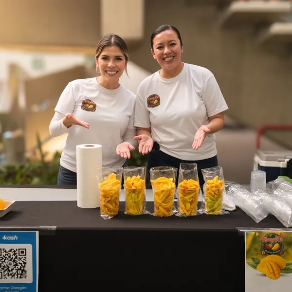 Dos personas del equipo Kash en un stand con vasos de mango