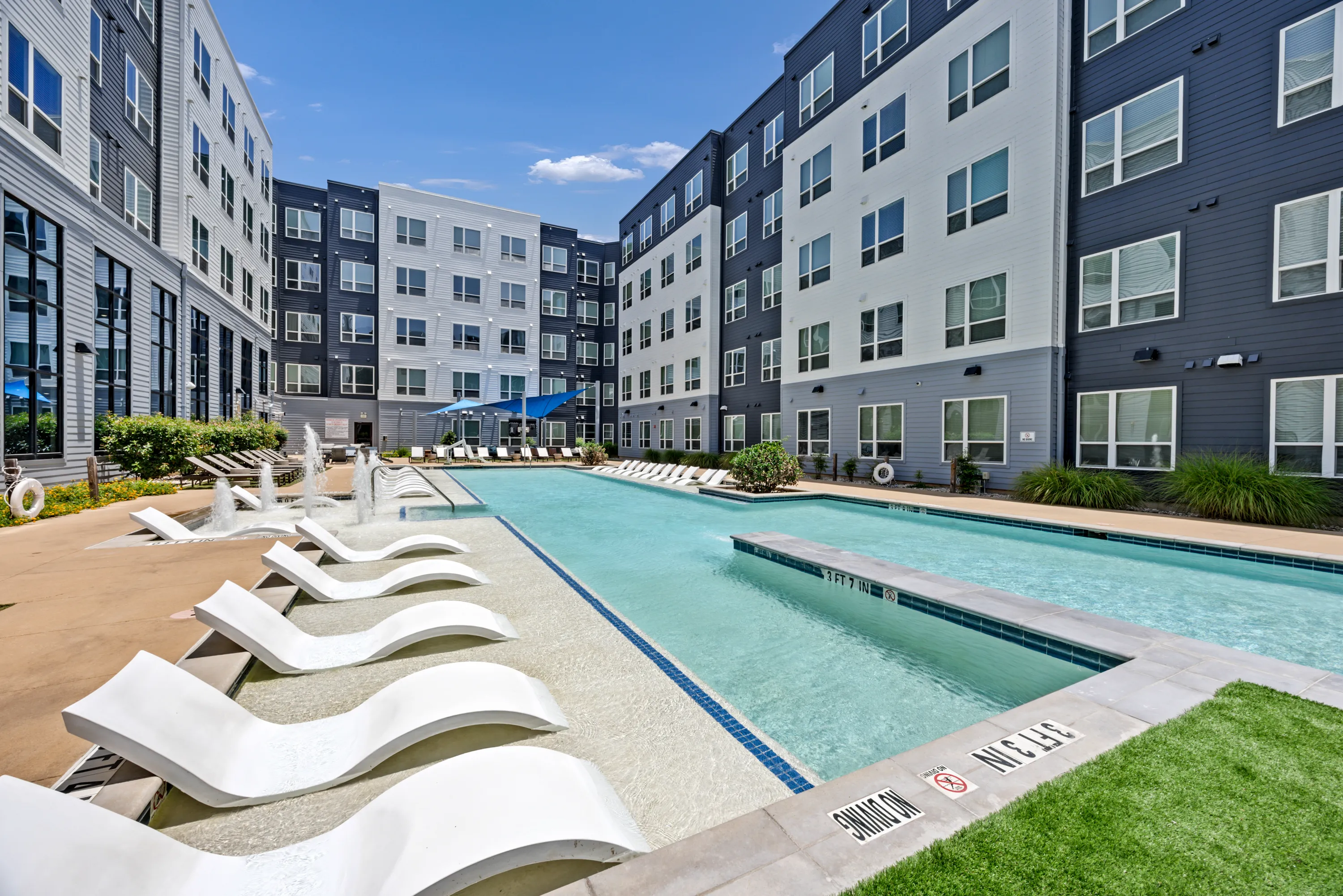 Swimming pool and poolside lounge chairs at The Den Student Living