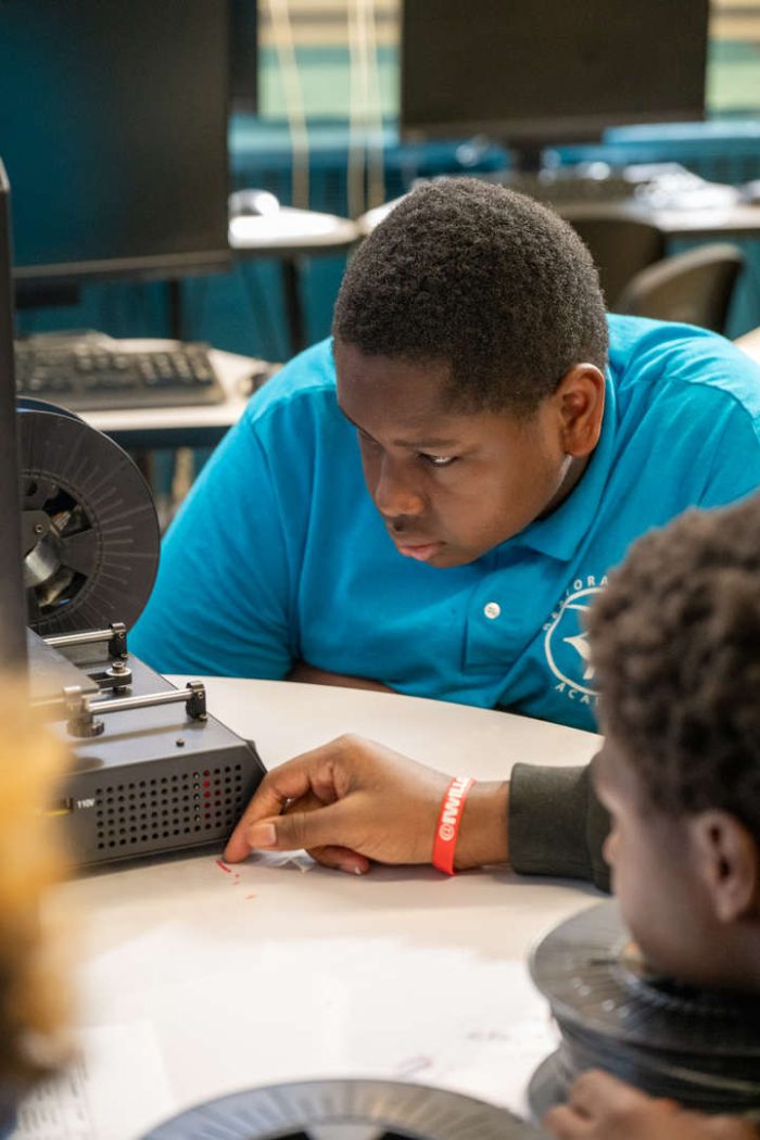 Teacher smiling and interacting with a young student in a classroom setting