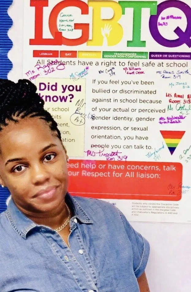 School counselor standing in front of LGBTQ student rights poster