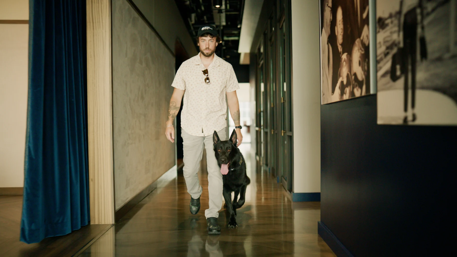Alex Bois, owner of CPI, walking with Able, a German Shepherd protection dog, indoors