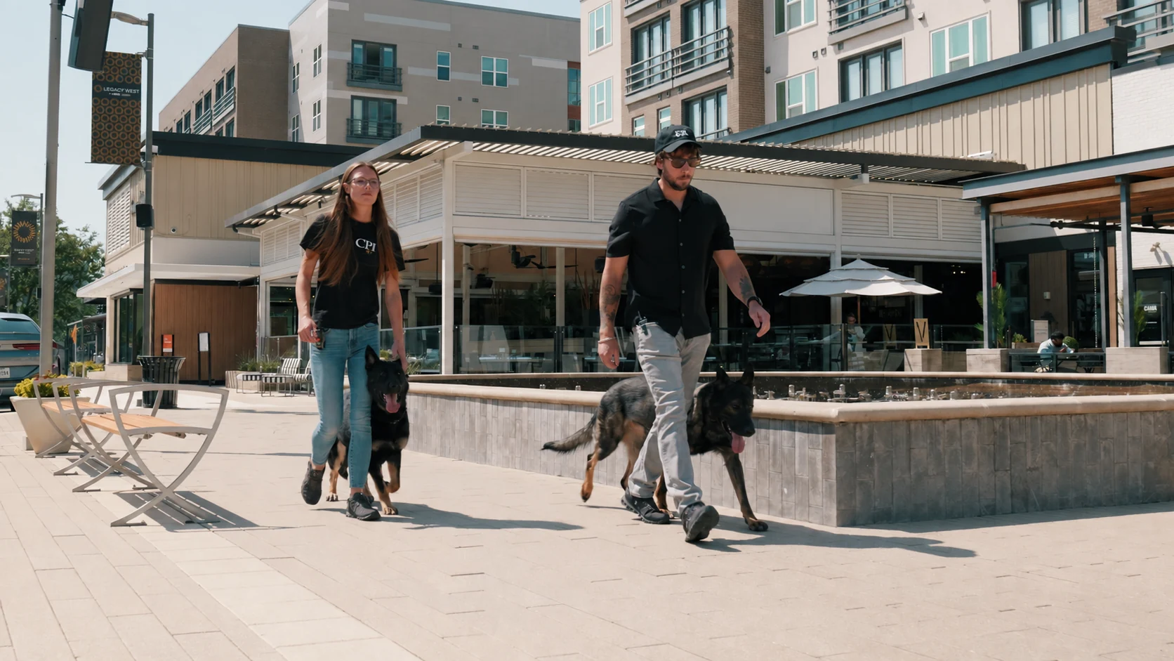 Alex and Abby walking CPI protection dogs calmly through a public shopping area