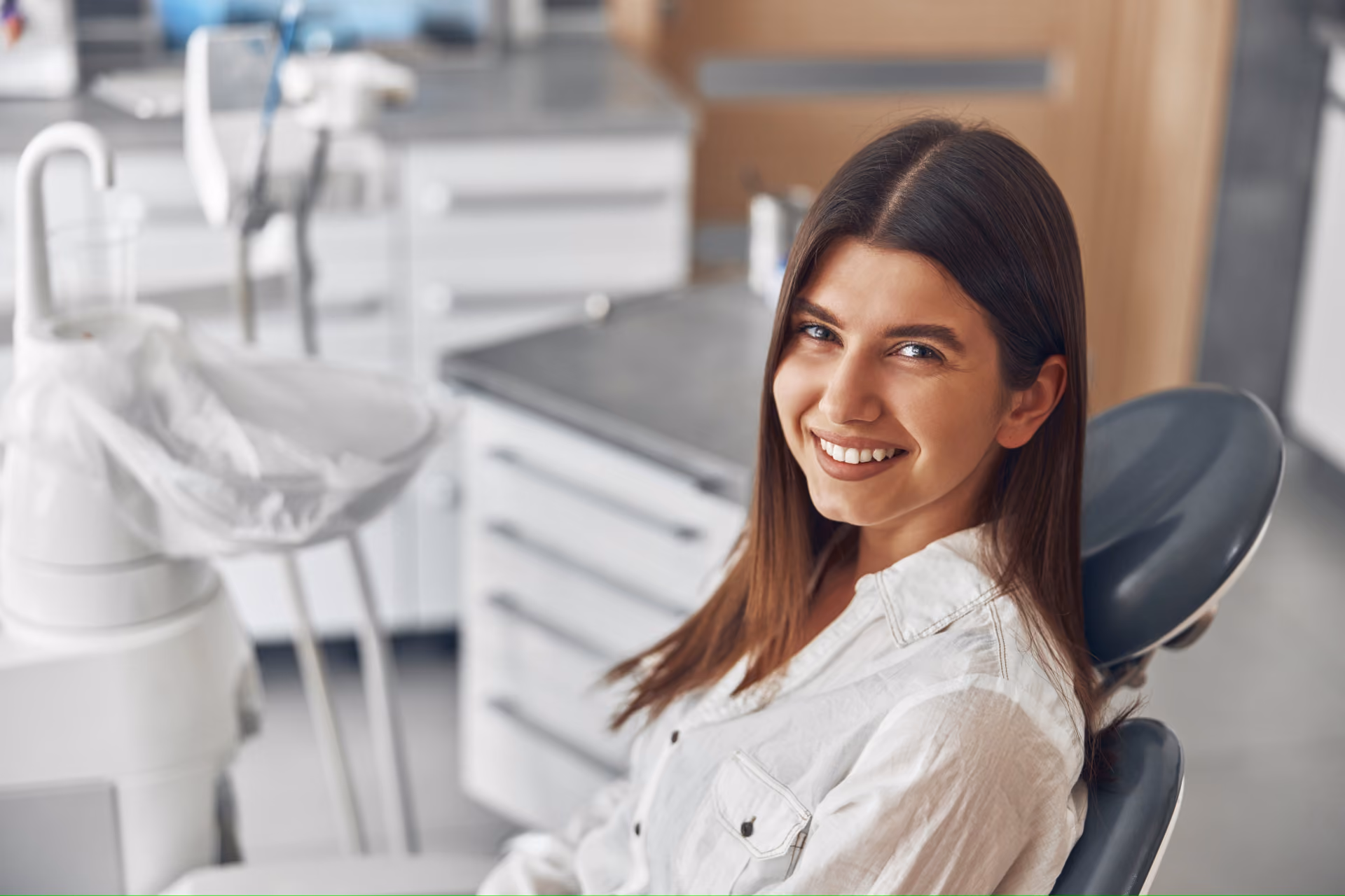 Smiling woman sitting in a dental chair in a bright dental office.