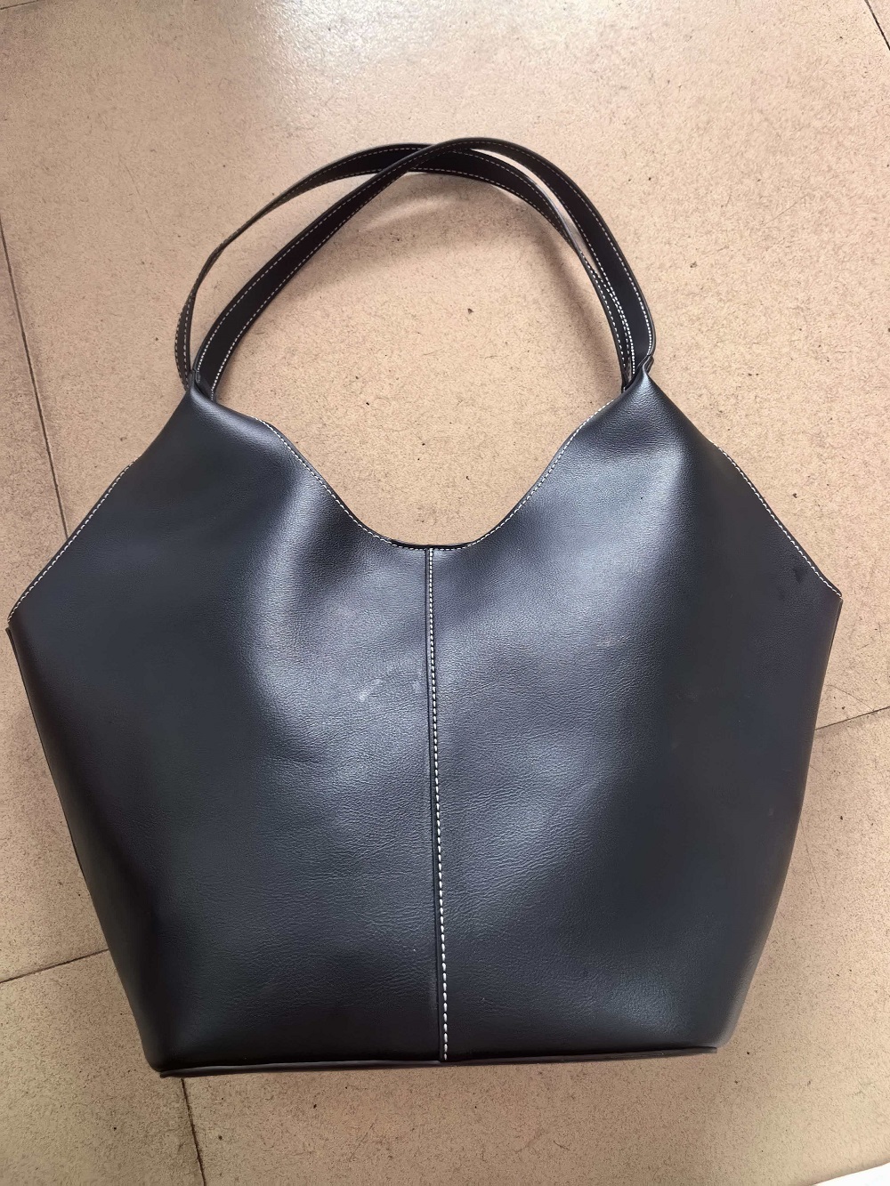 Black leather hobo tote bag displayed on model with shoulder strap