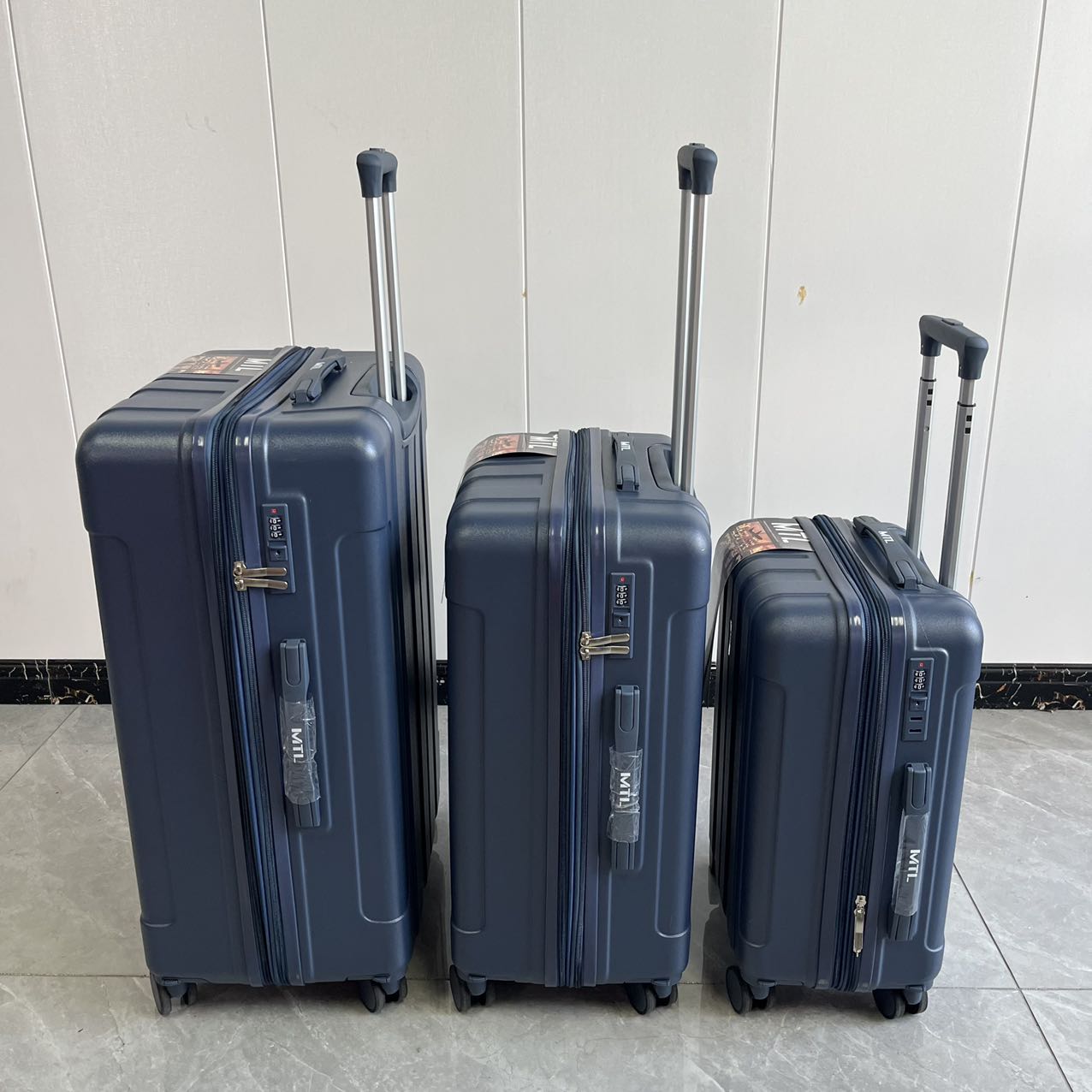 Side perspective view of blue trolley suitcases in three sizes