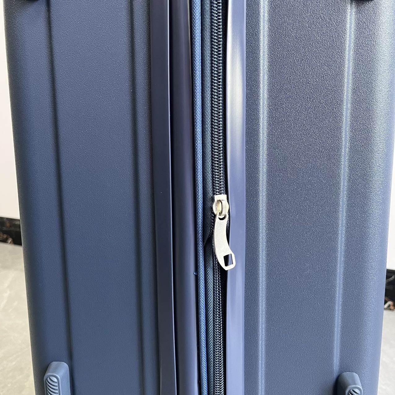 Close-up view of blue hard-shell suitcase side handle and lock detail