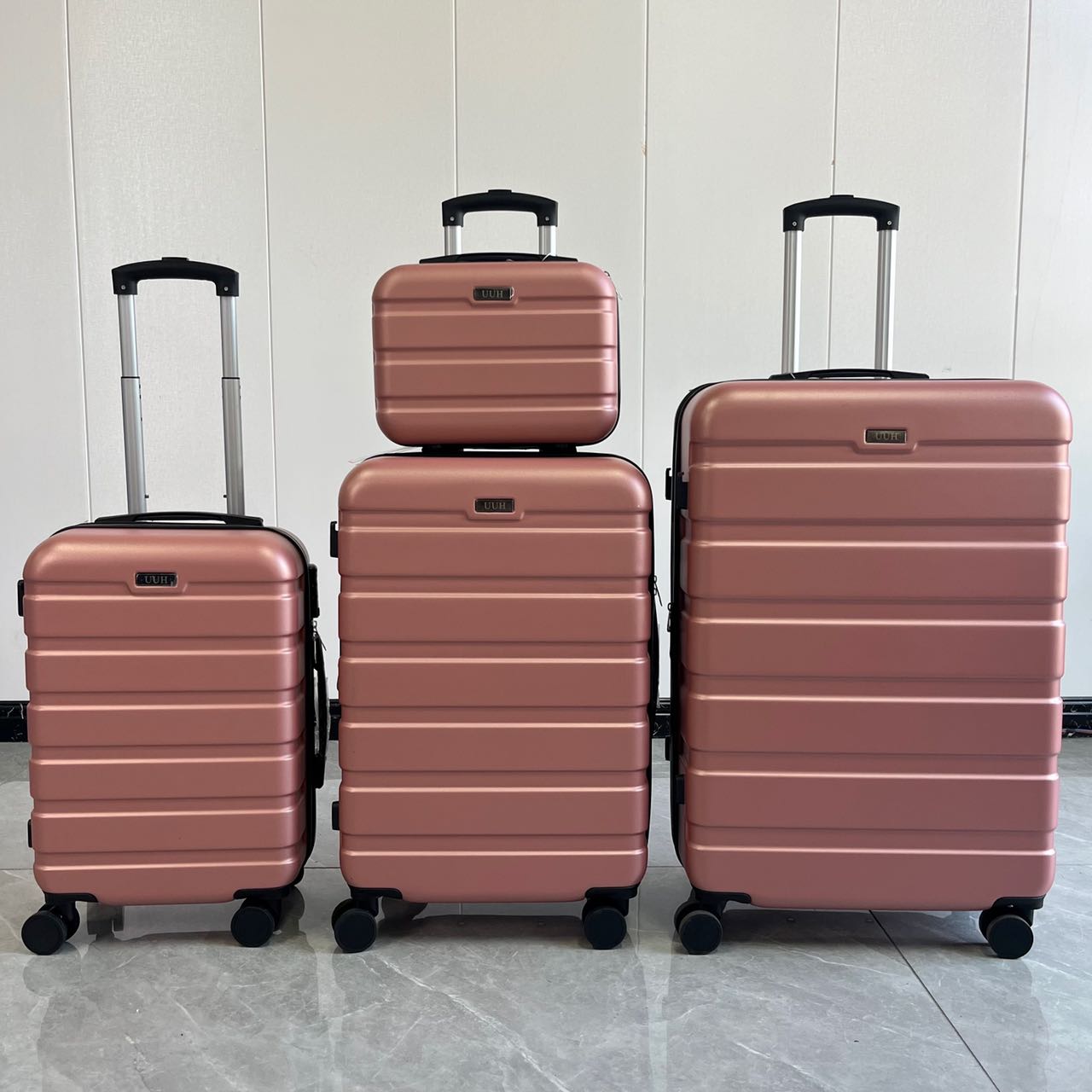 Rose gold 4-piece hard-shell trolley suitcase set displayed outdoors