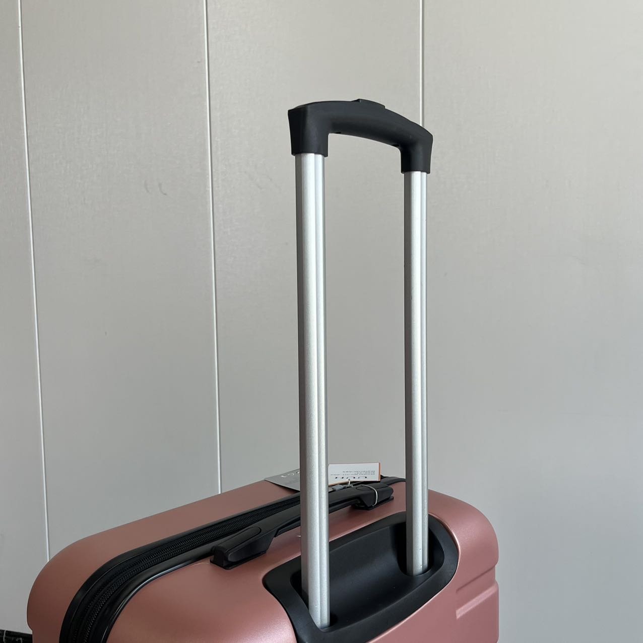 Close-up detail of extended telescopic handle on rose gold suitcase