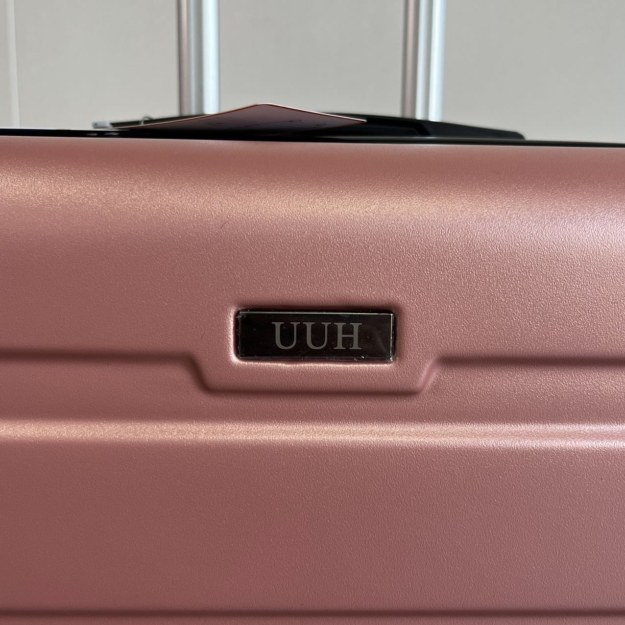 Close-up view of rose gold suitcase carrying handle and textured shell