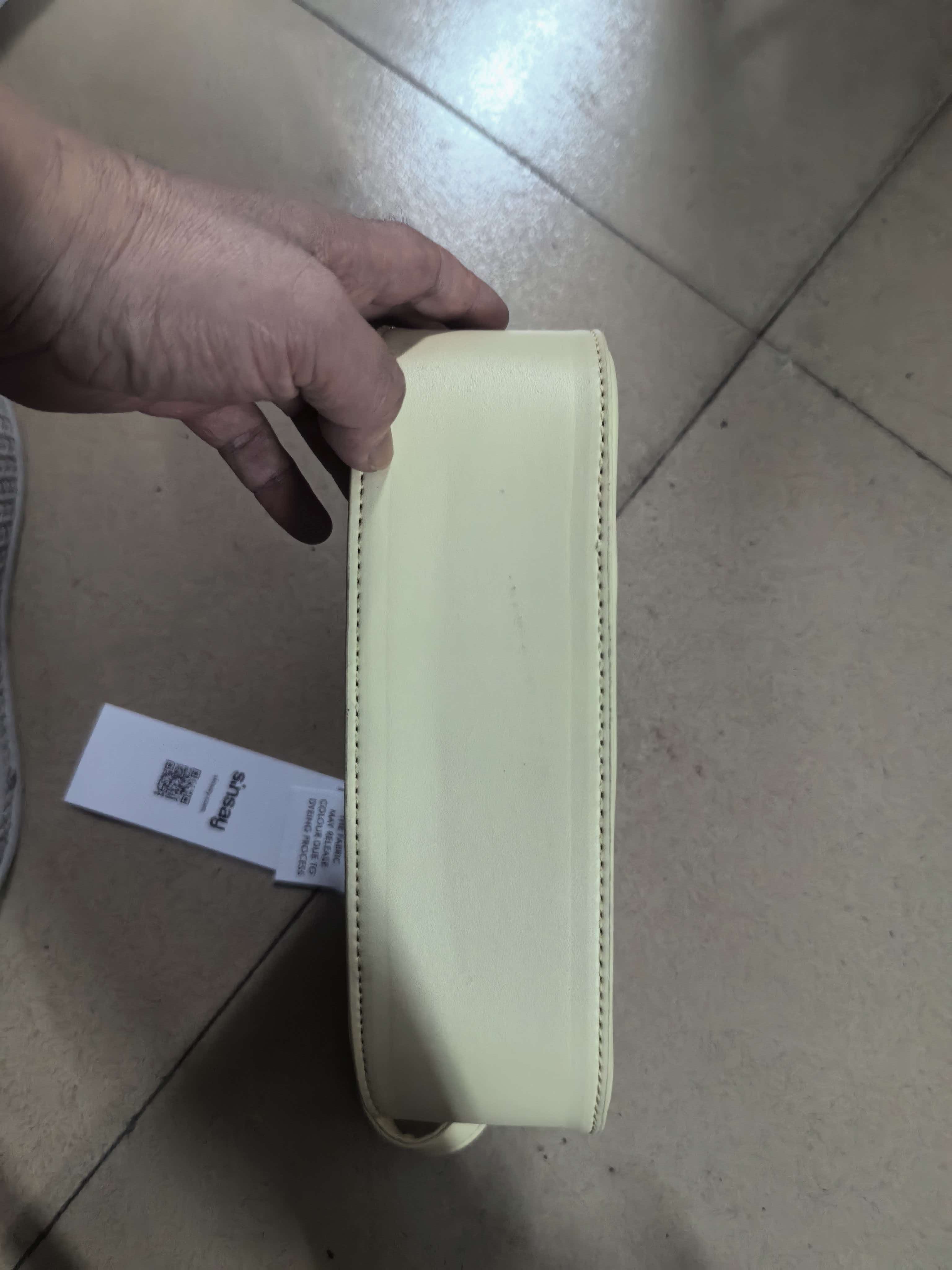 Person holding cream hobo shoulder bag showing its size and fit