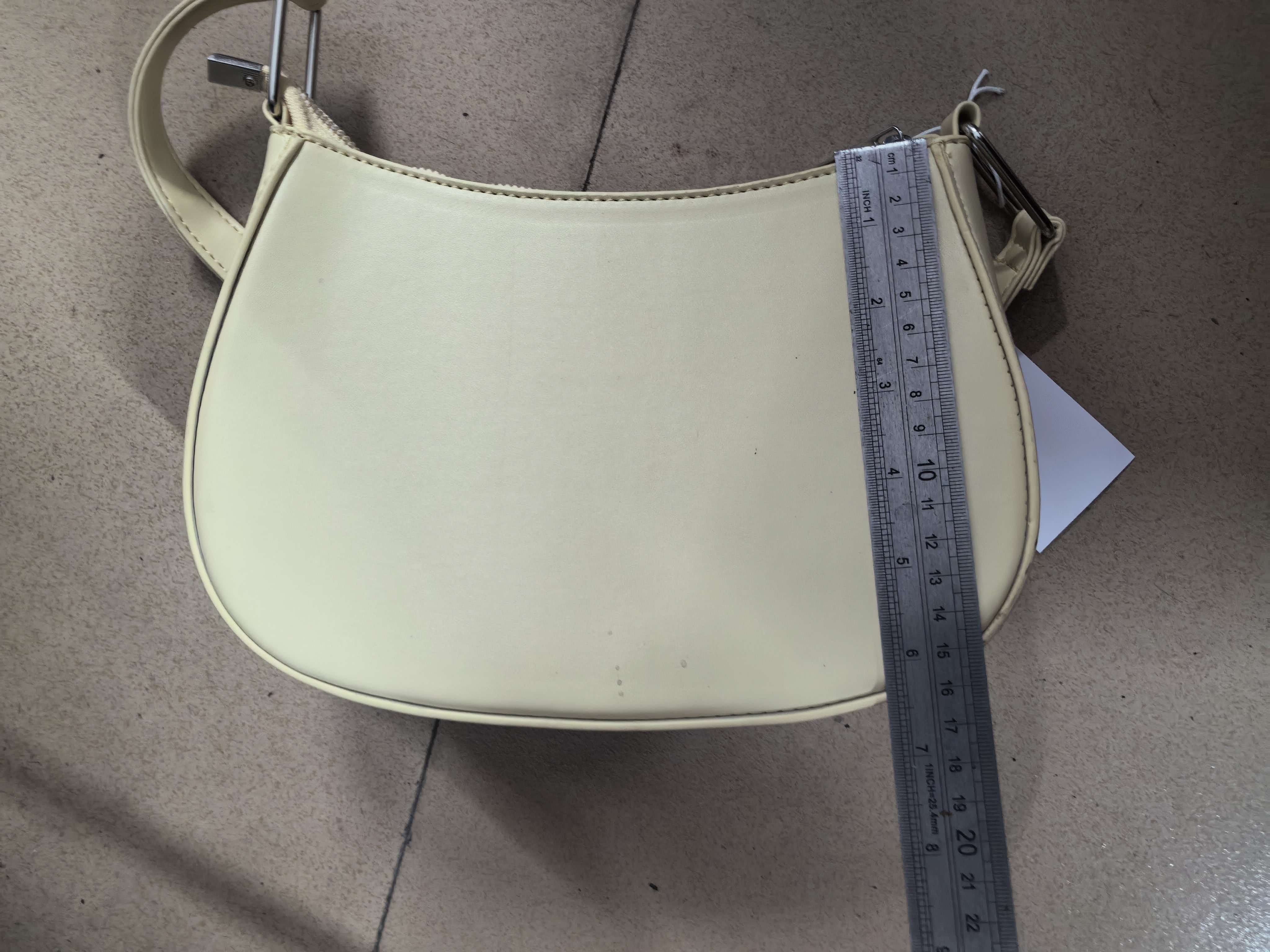 Front view of cream hobo bag displaying product tag and shoulder strap