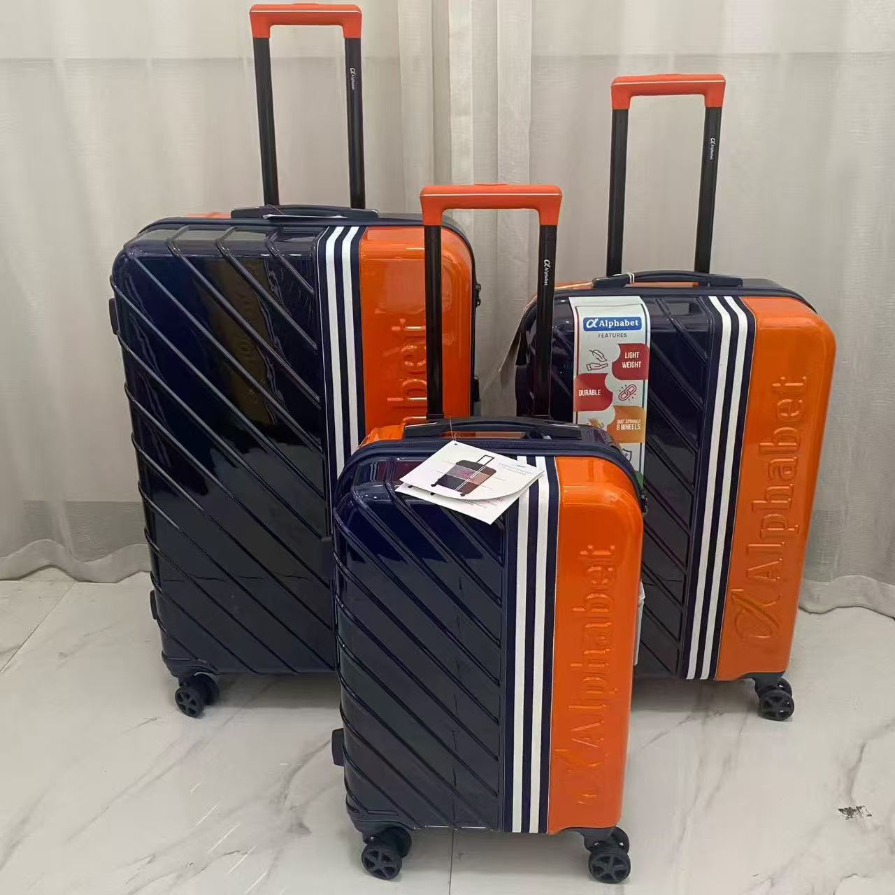 Side perspective view of red yellow and orange hard-shell spinner suitcases