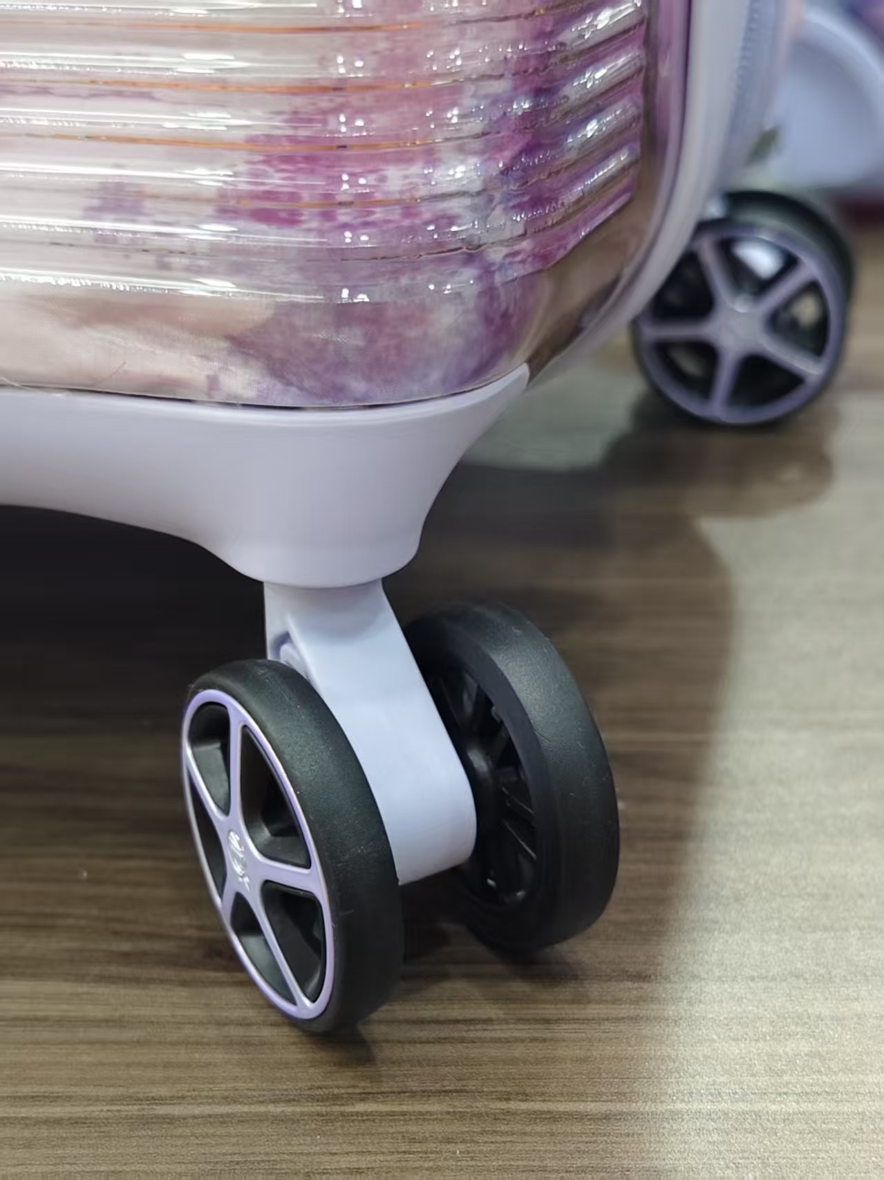 Close-up detail of spinner wheel and lower corner of suitcase