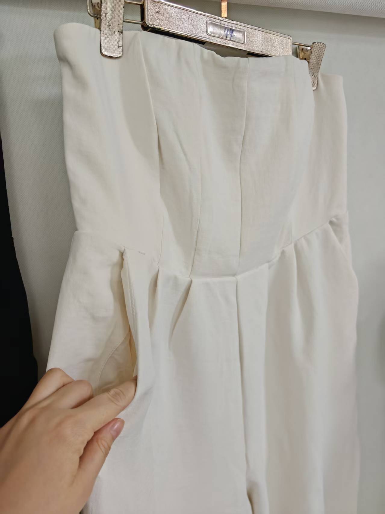 Upper body close-up detail of off-white strapless jumpsuit top and neckline