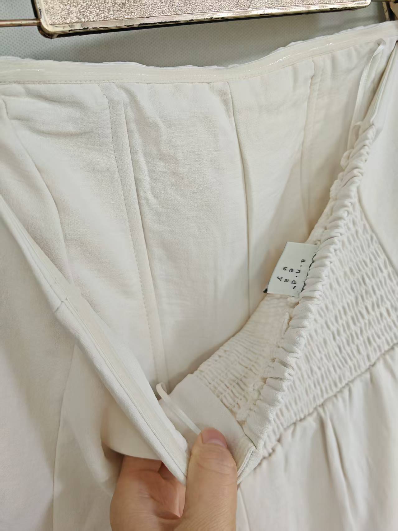 Close-up detail of off-white strapless jumpsuit fabric and waist seam