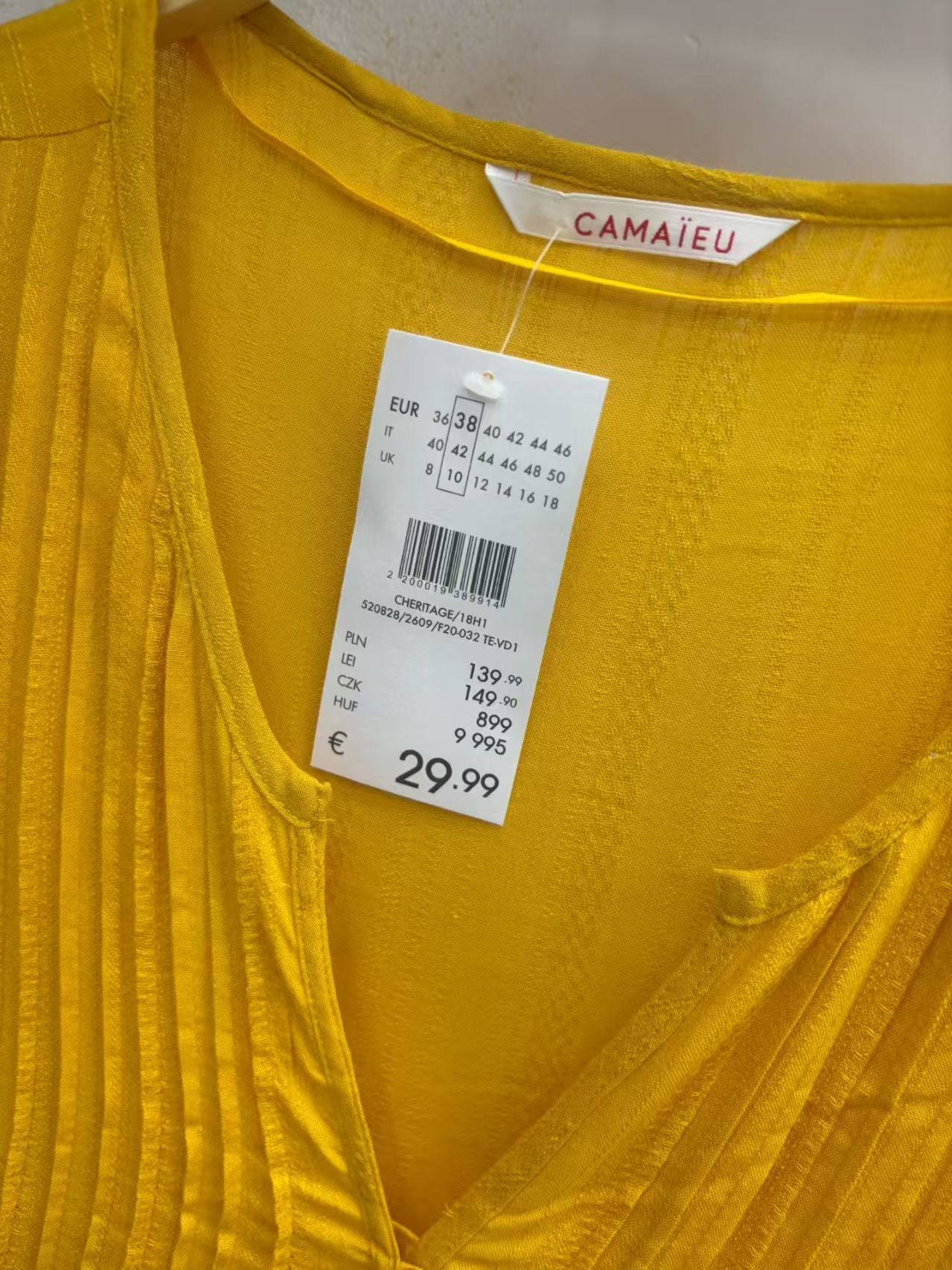 Close-up view of mustard yellow ladies' blouse neckline and clothing tag