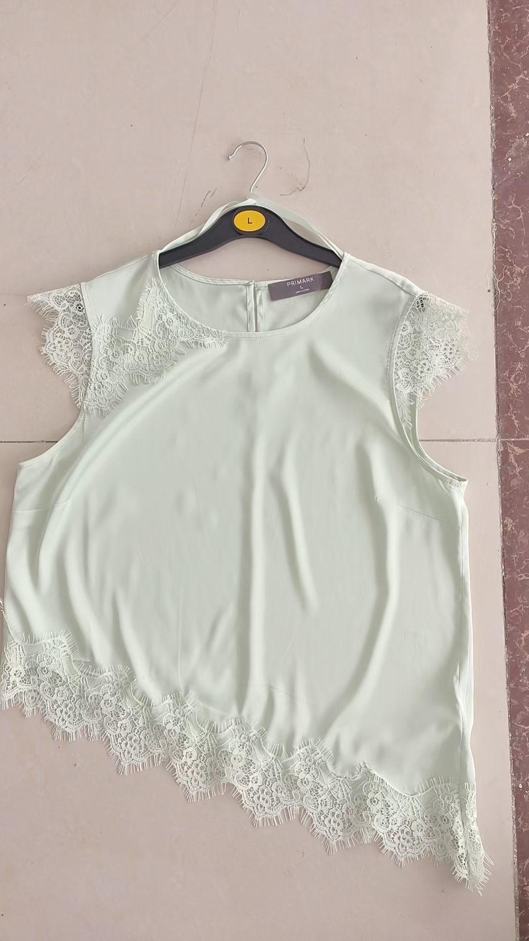 White ladies' short sleeve blouse displayed flat on a white hanger