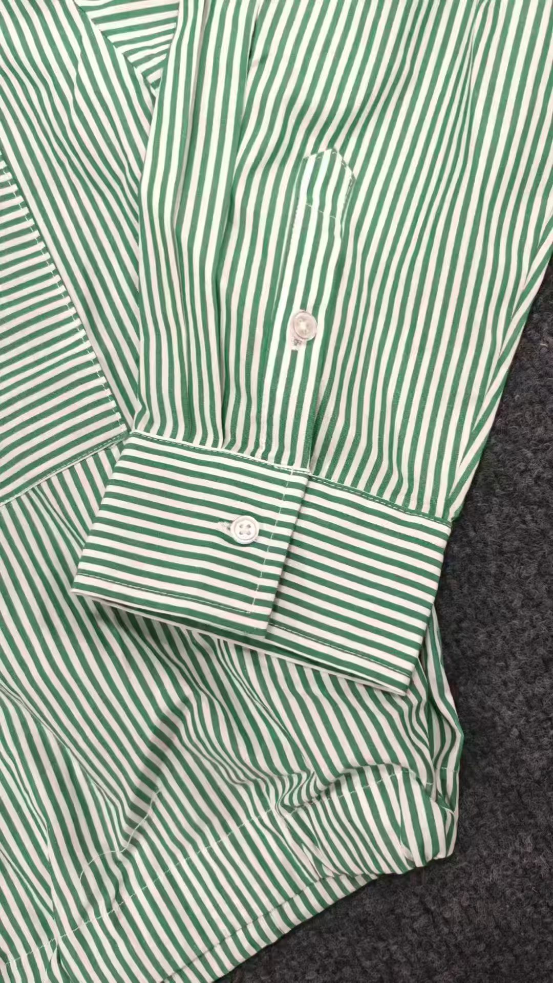 Side detail view of green striped ladies' blouse sleeve and side tie