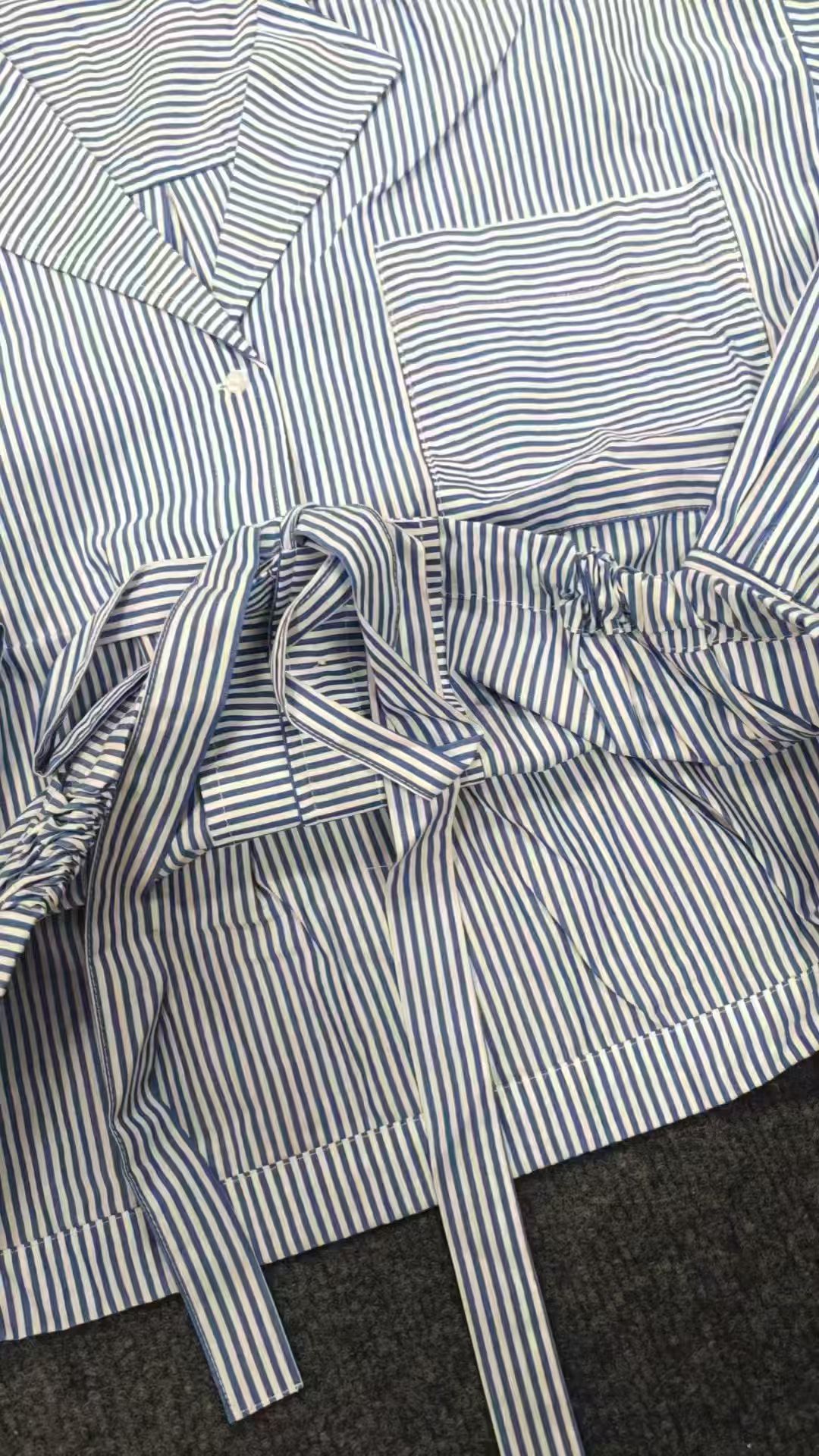 Close-up detail of light blue striped ladies' blouse sleeve and shoulder seam