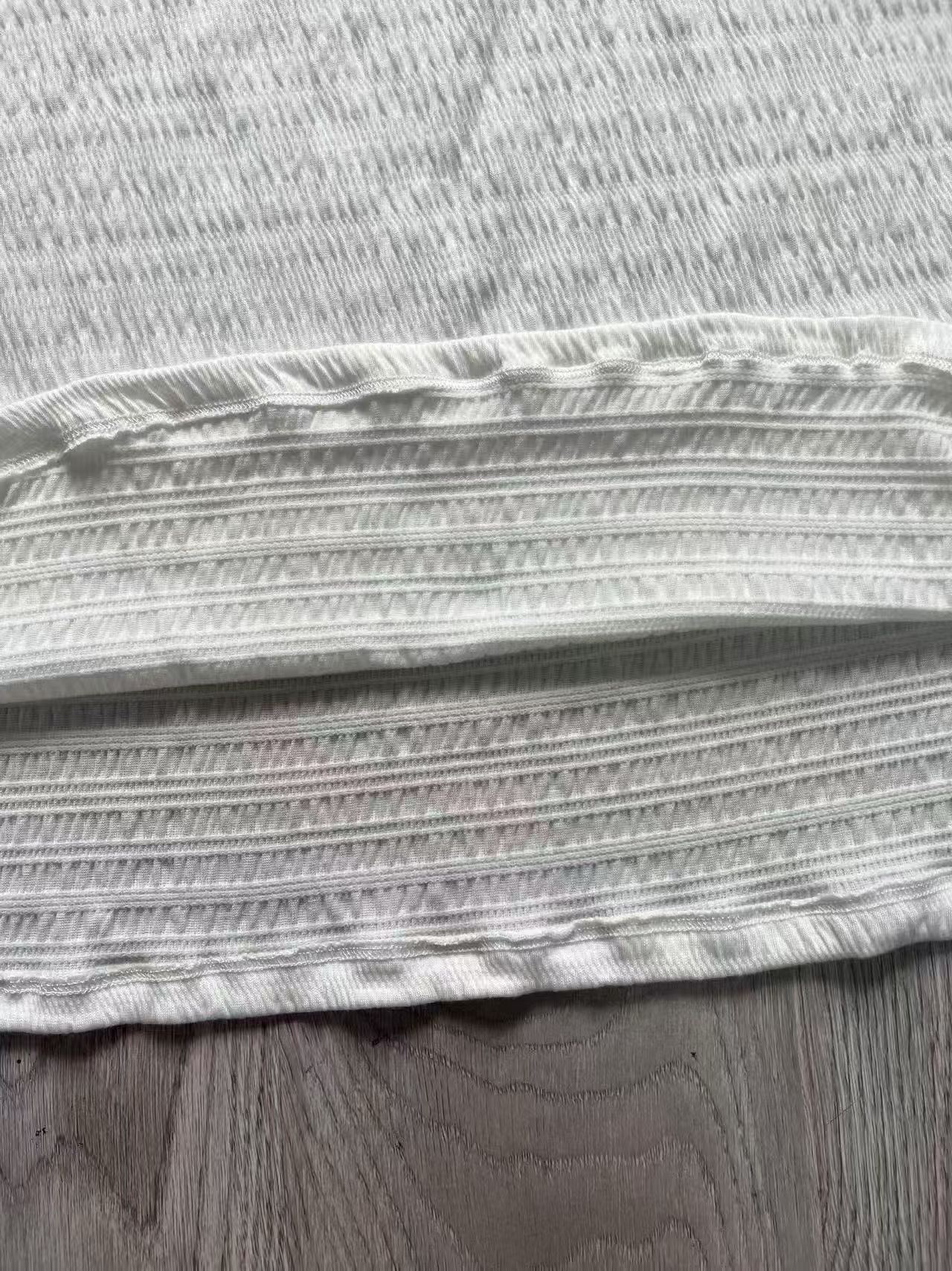 Close-up view of textured fabric and pleat details on white ladies' blouse
