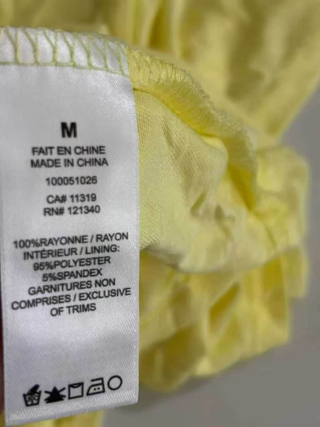 Close-up view of yellow ladies' blouse neck collar and clothing tag