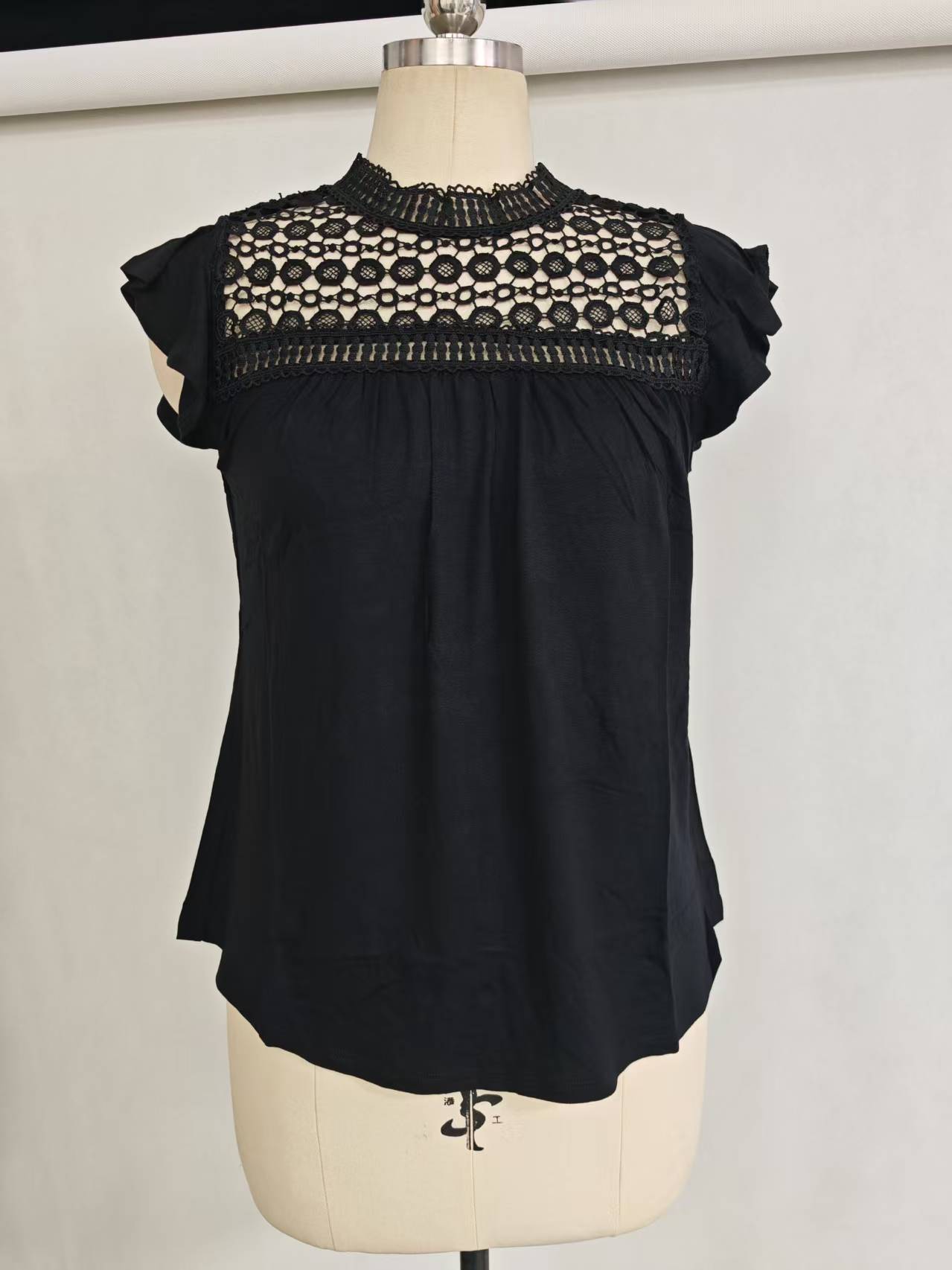 Black ladies' short sleeve rayon blend blouse with lace shoulder panel displayed flat
