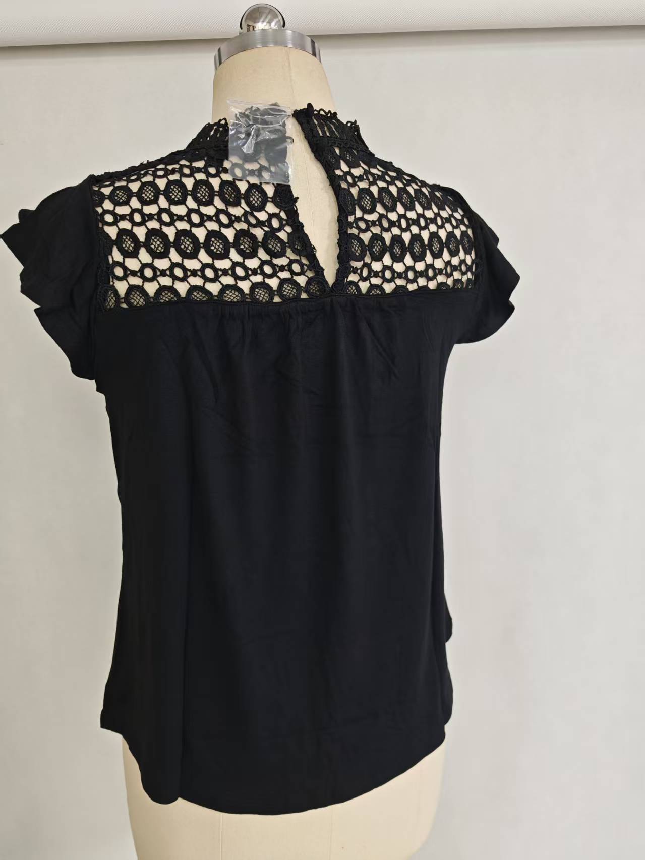 Black ladies' short sleeve blouse with lace trim details displayed flat
