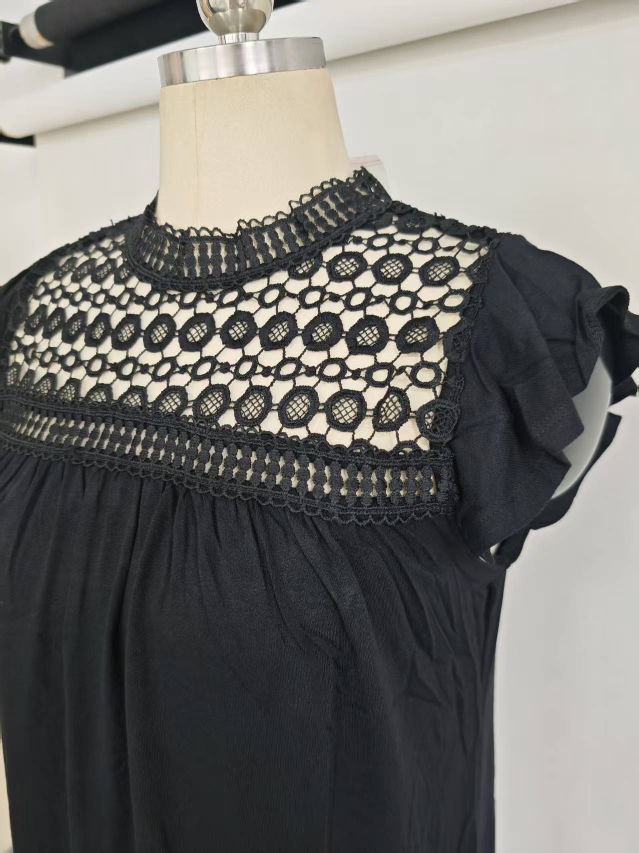 Close-up detail of lace neckline and sleeve trim on black ladies' blouse on mannequin