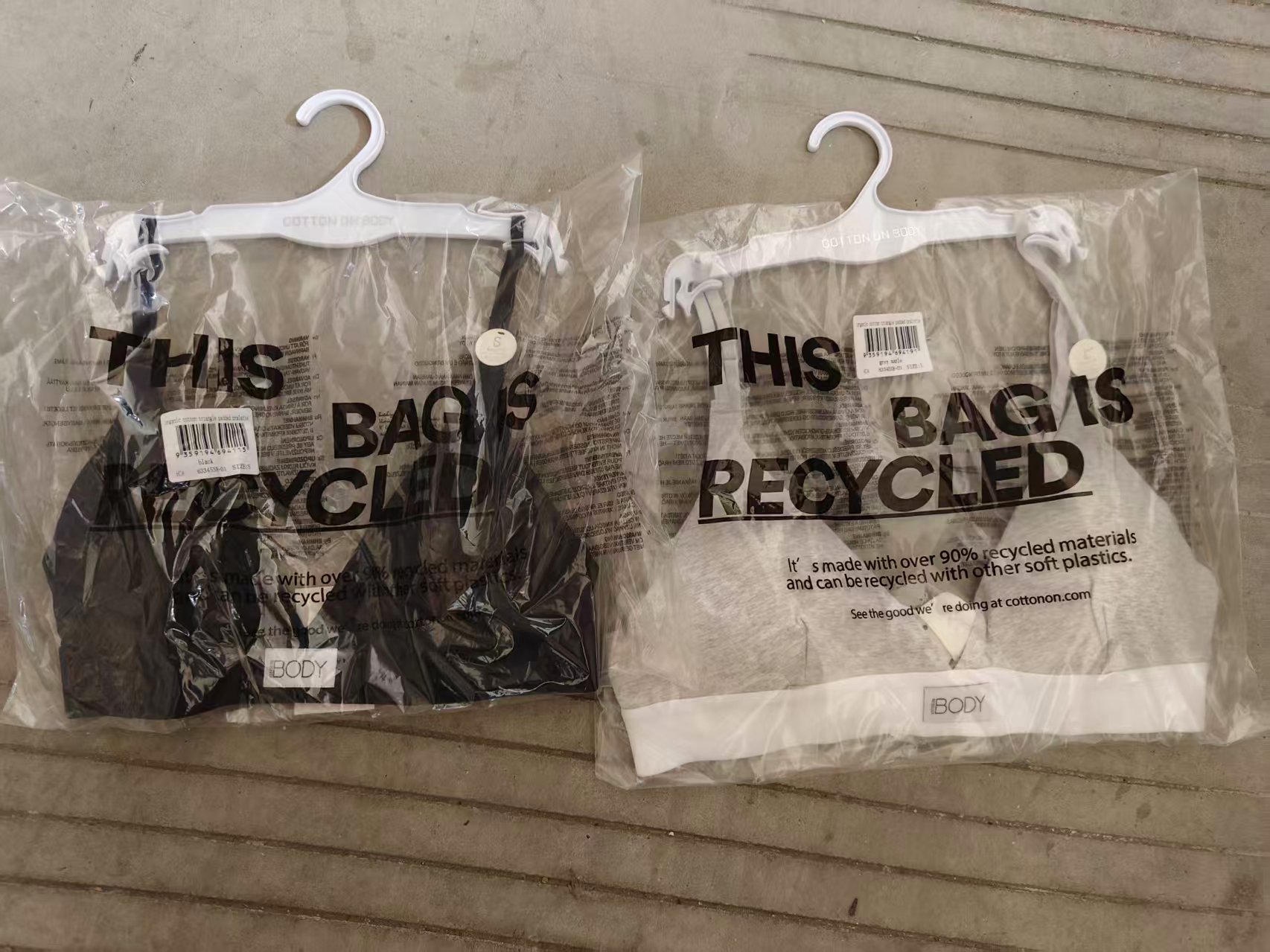 Black and grey organic cotton ladies' bras individually packed in clear polybags on hangers