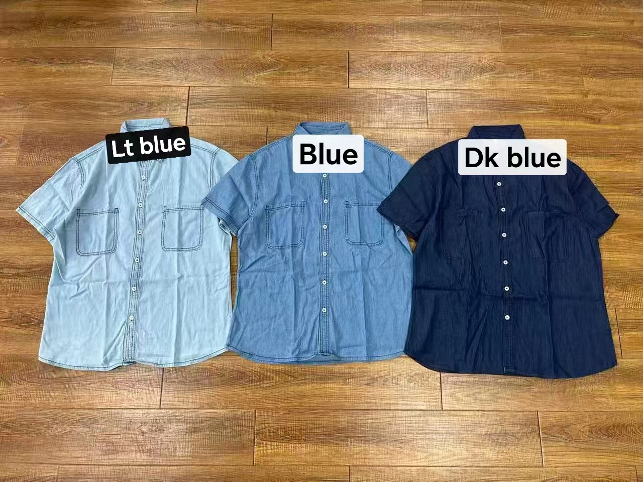 Men's cotton short sleeve shirts displayed together in blue, light blue, and dark blue on clothing rack