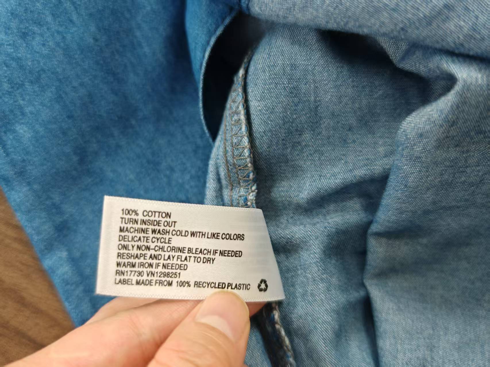 Close-up detail of dark blue men's cotton shirt fabric and brand care label