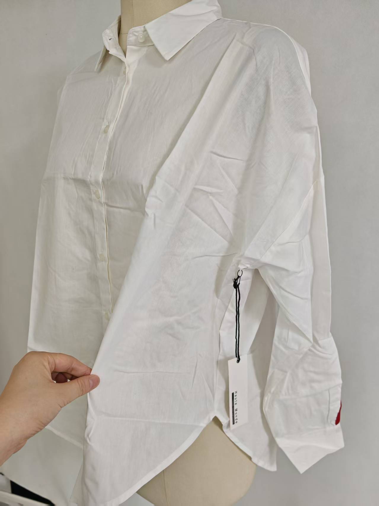 White ladies' long sleeve cotton shirt displayed on a hanger