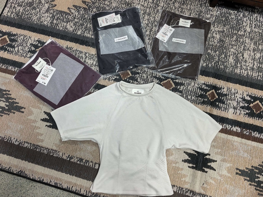 White, black, coffee, and burgundy ladies' t-shirts displayed together flat with clothing tags