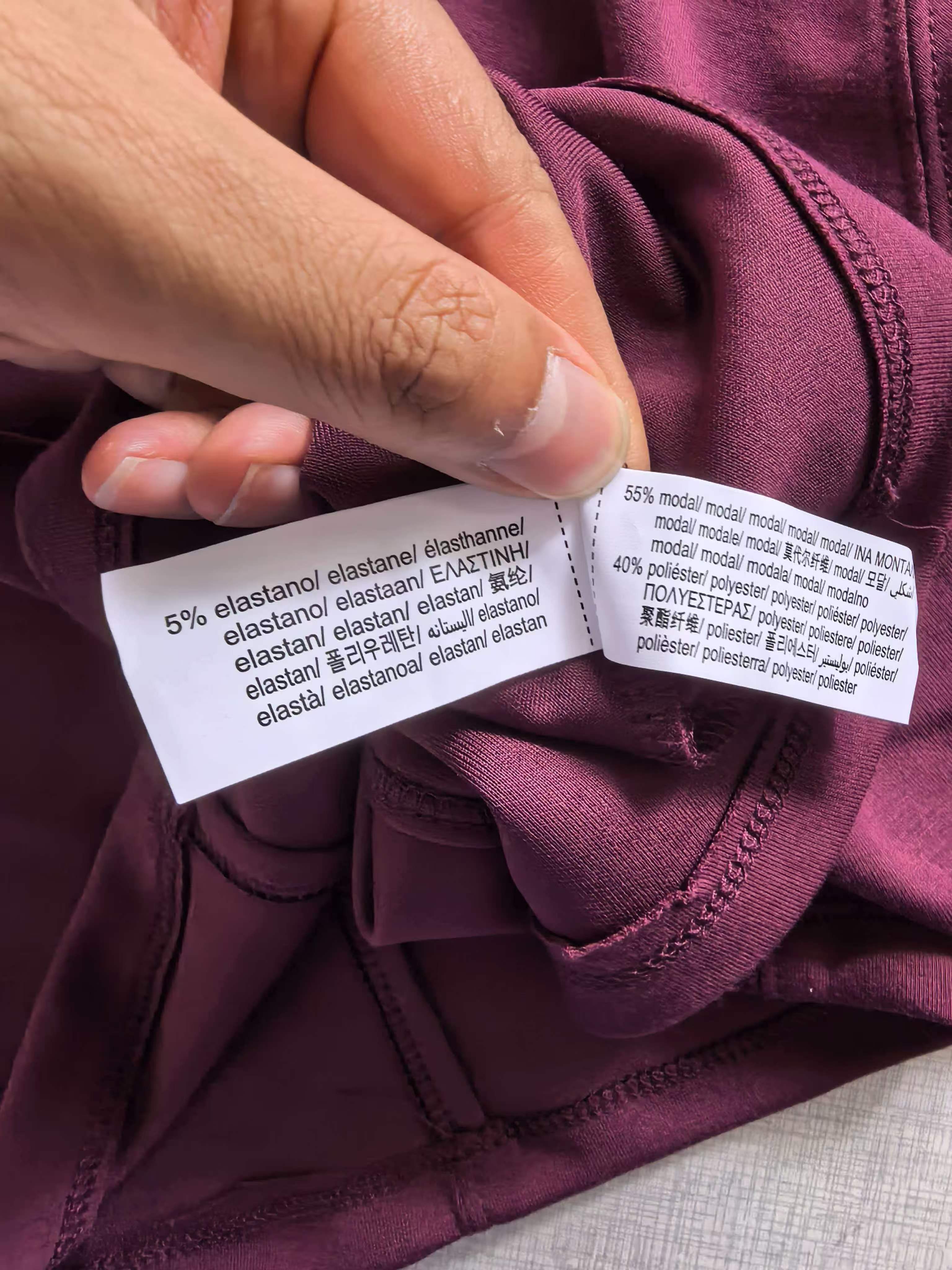 Close-up detail of burgundy ladies' t-shirt collar seam and clothing brand label