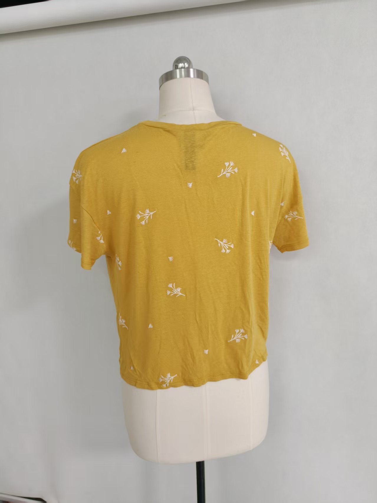 Back view of mustard yellow ladies' short sleeve t-shirt displayed on a mannequin