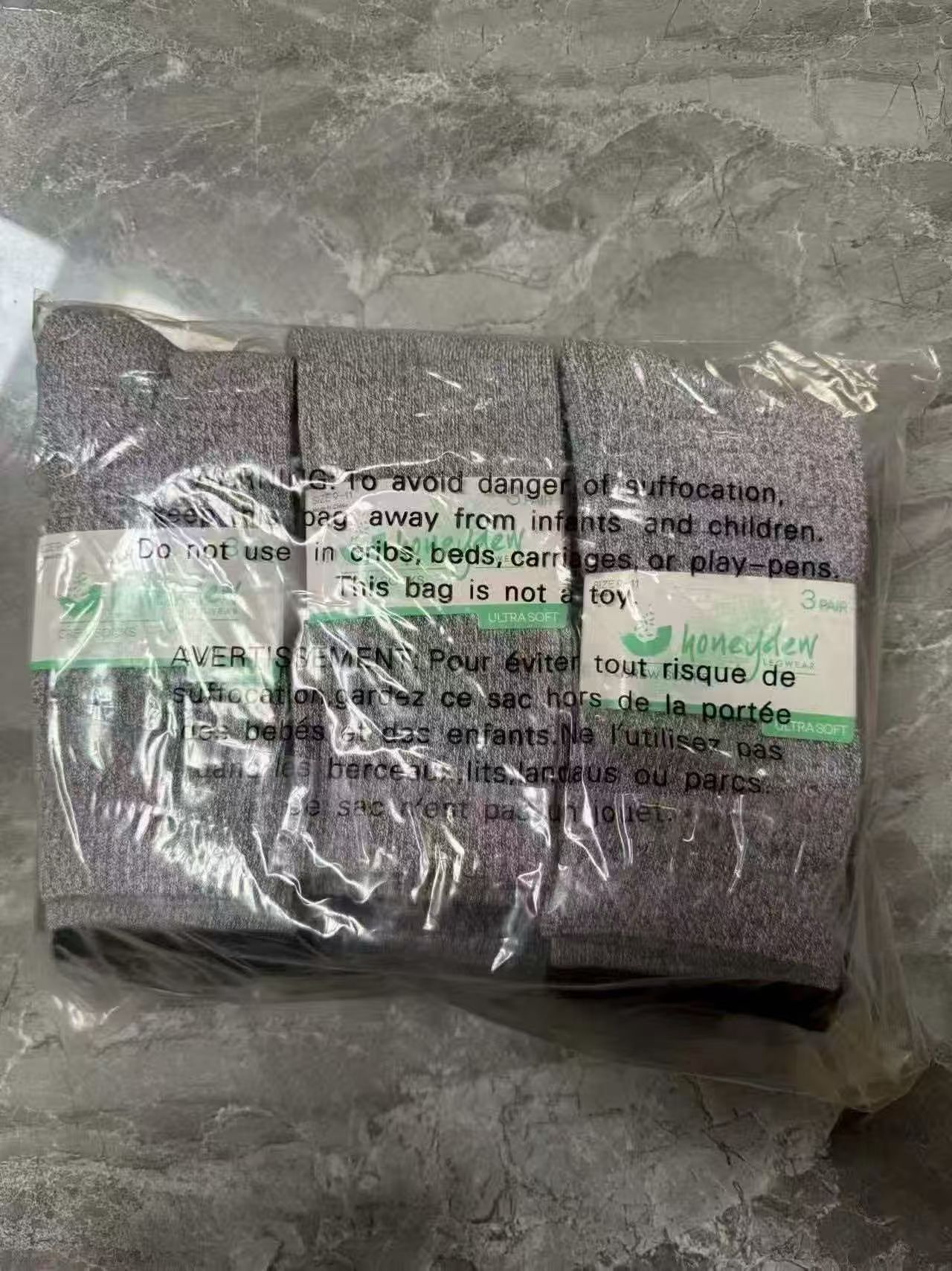 Multiple pairs of ladies' low cut socks in black, white, and grey packed in clear polybags