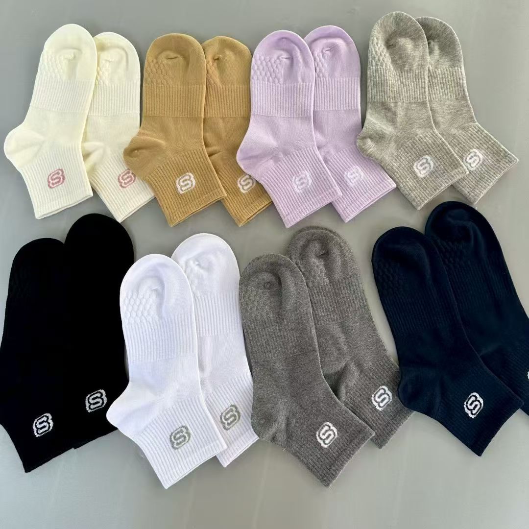 Multiple pairs of ladies' socks in black, white, grey, camel, navy, and purple arranged together flat