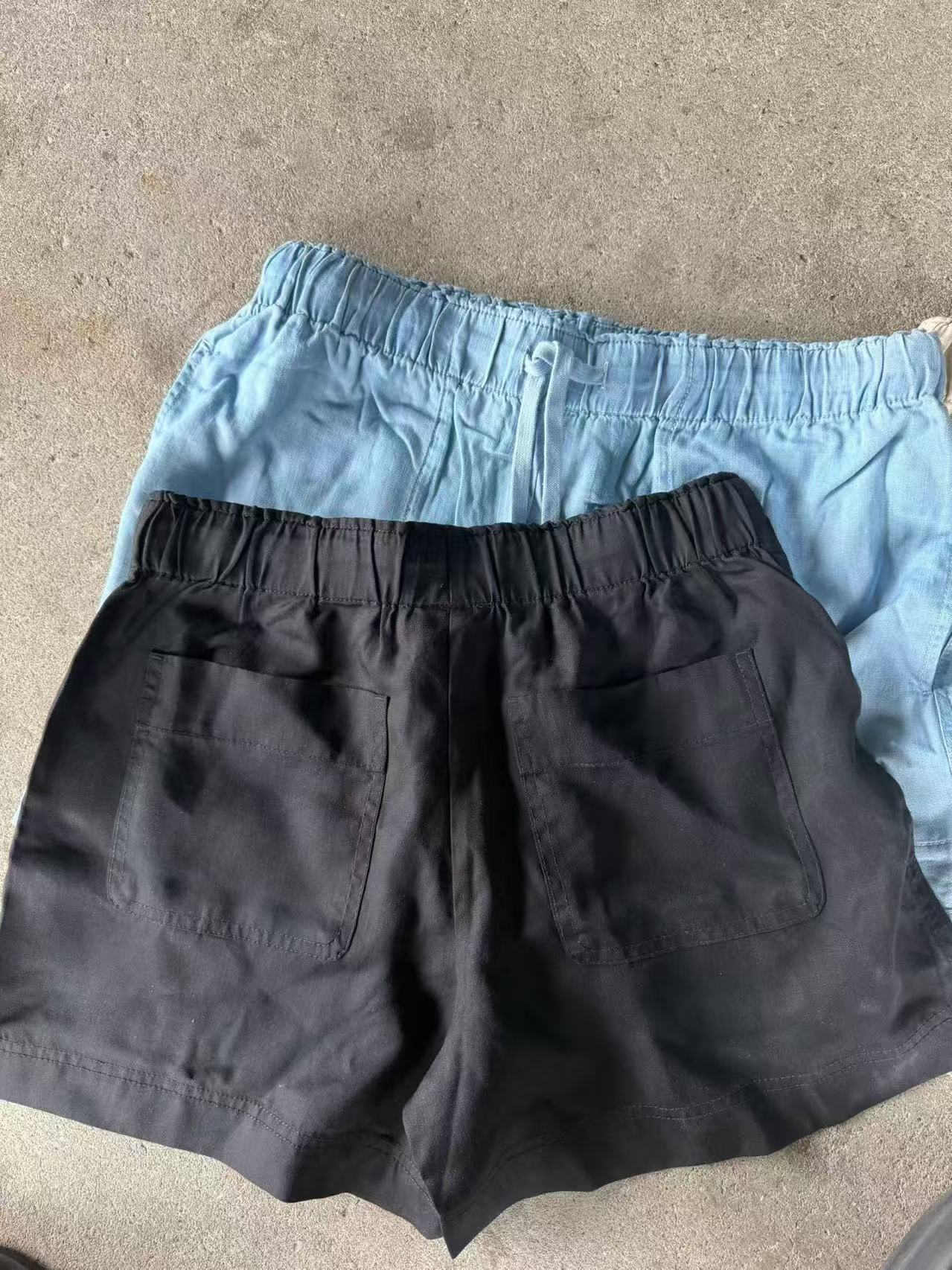 Off-white and black women's Tencel shorts stacked and laid flat.