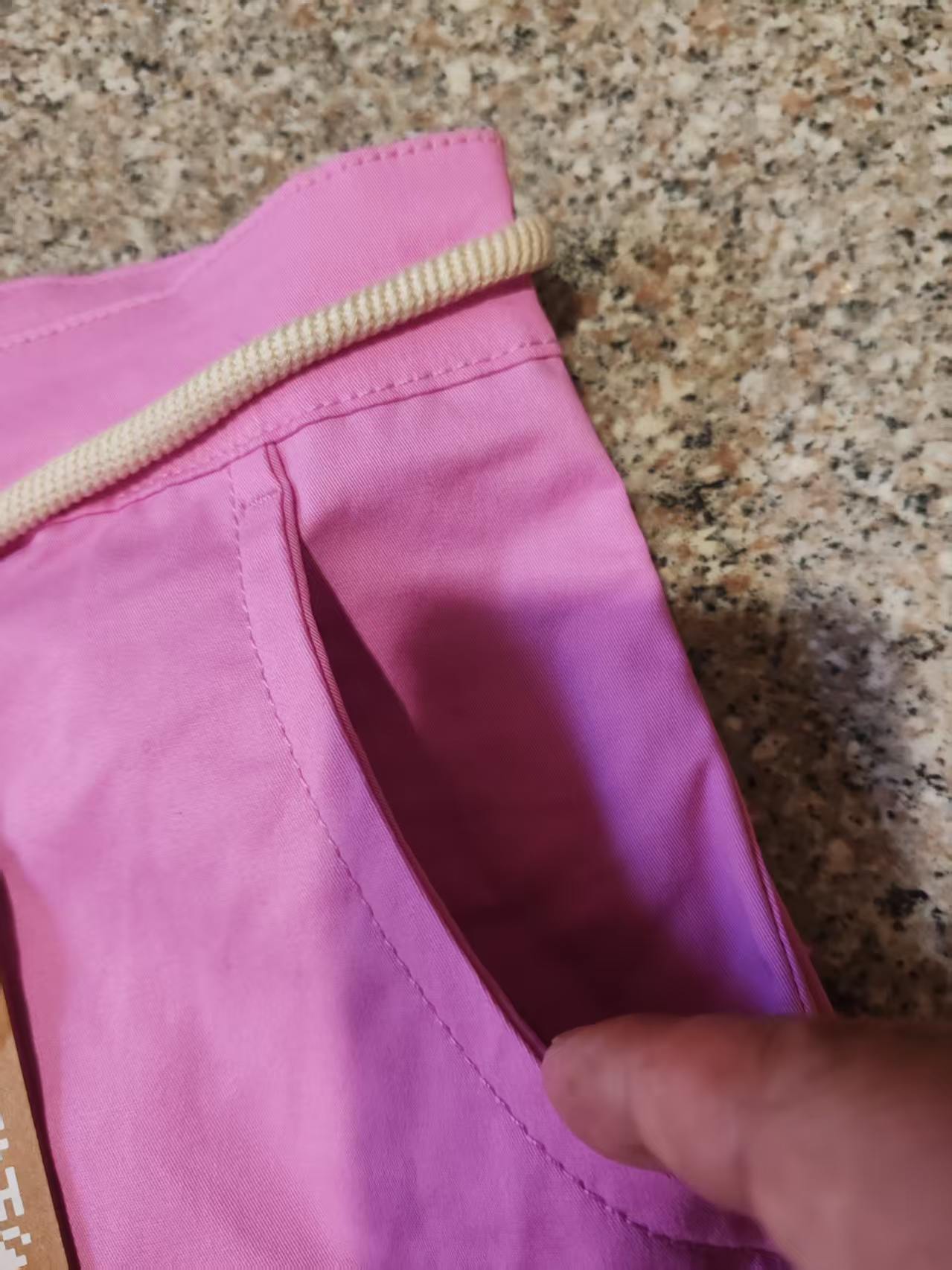 Close-up of pink women's casual shorts showing the elastic drawstring waistband and fabric texture.