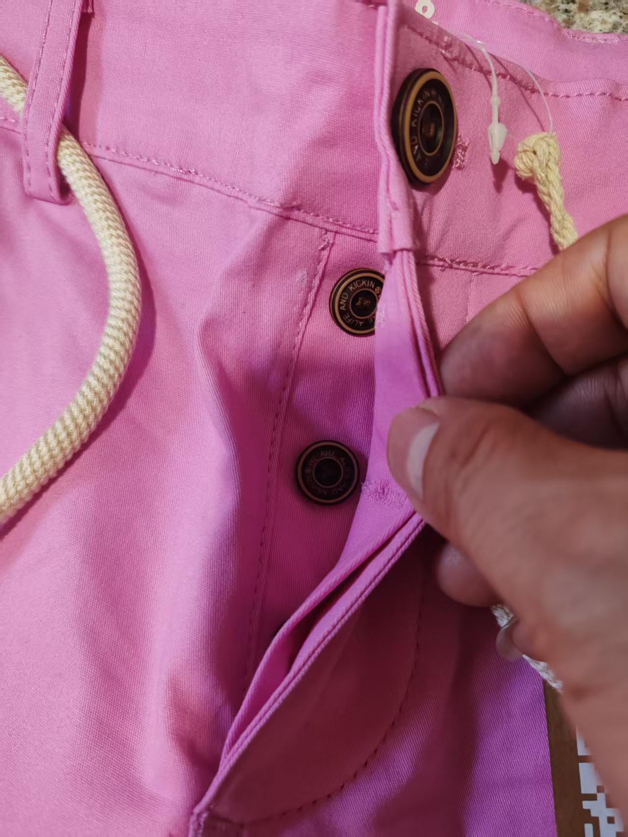 Close-up detail of the button closure and waistband structure on pink women's shorts.