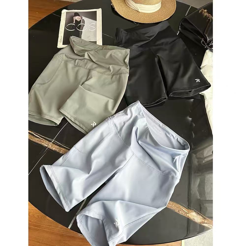 Women's athletic shorts in light blue, dark blue, and olive green stacked and laid flat.