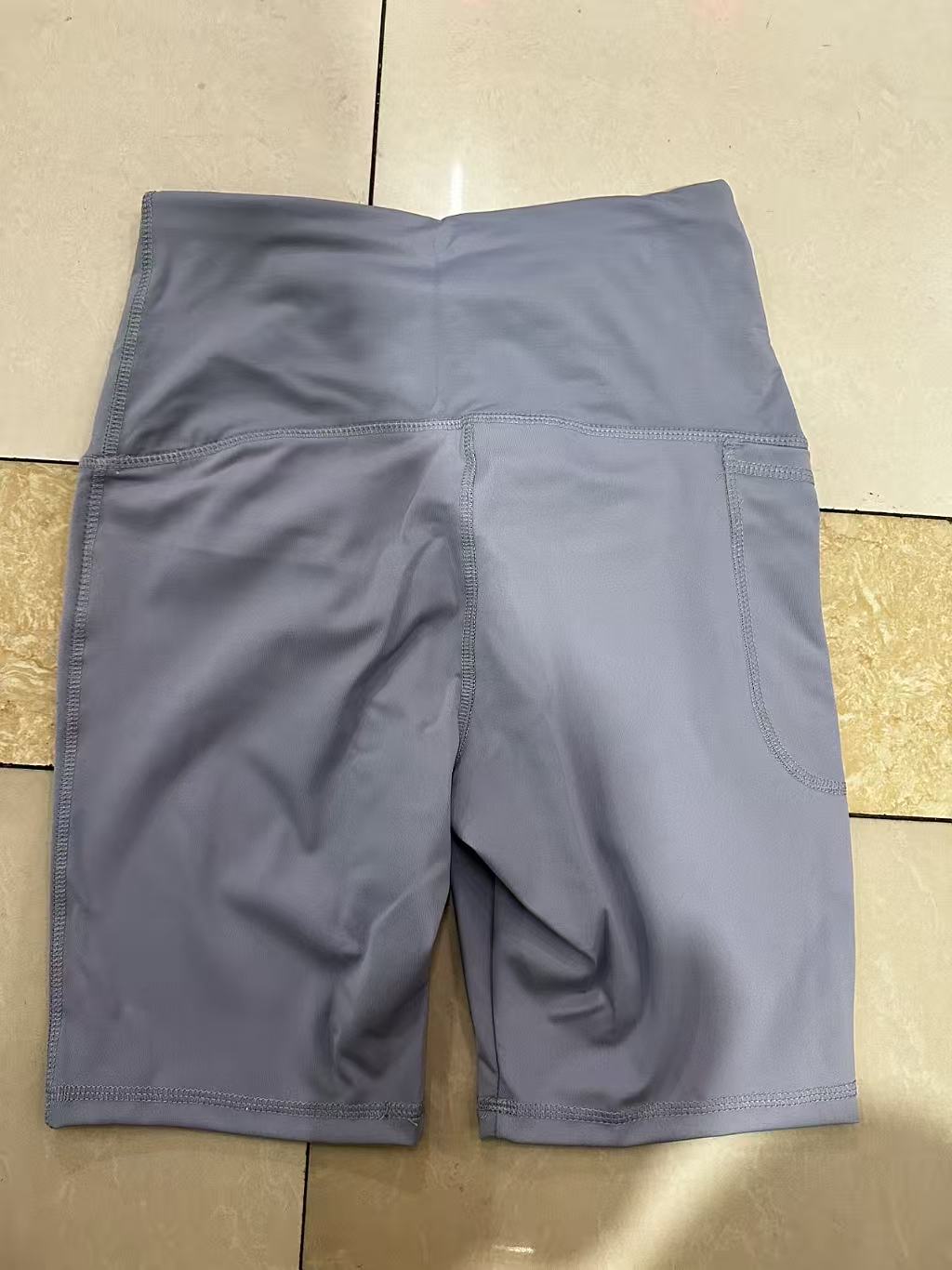 Close-up of dark blue women's athletic shorts showing the elastic waist and front drawstring closure.