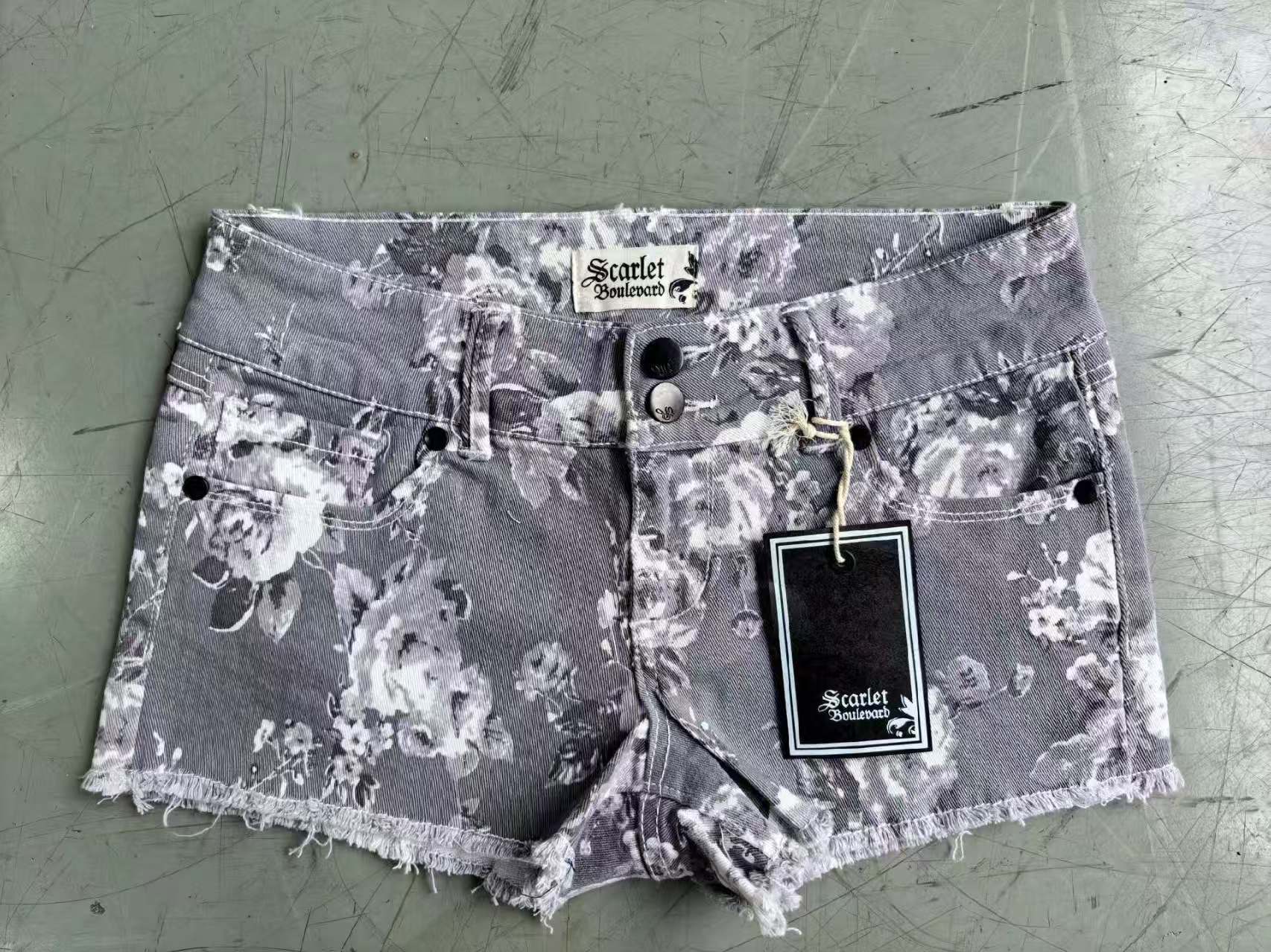 Women's denim shorts with folded hem in blue, grey, and purple stacked and laid flat.