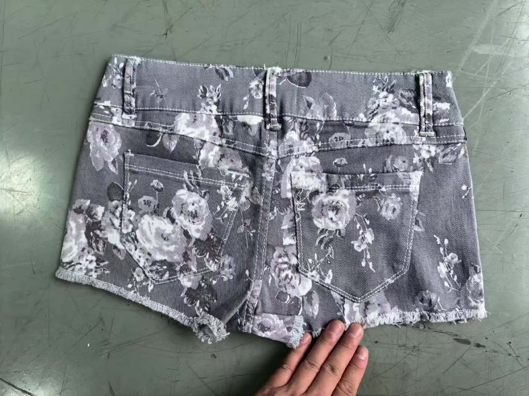 Close-up of blue, grey, and purple women's denim shorts showing front button fly and pocket details.