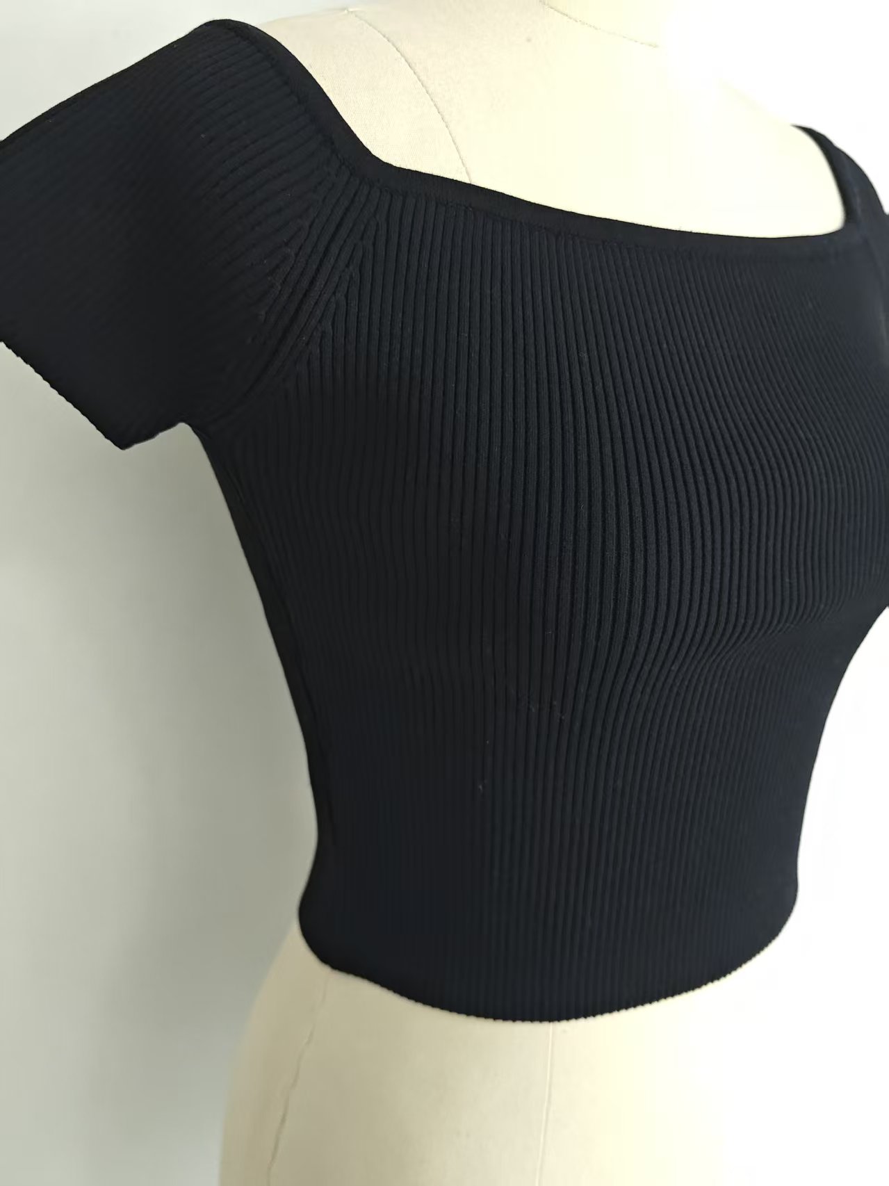 Side view detail of the black women's ribbed crop top on a mannequin showing sleeve cut.