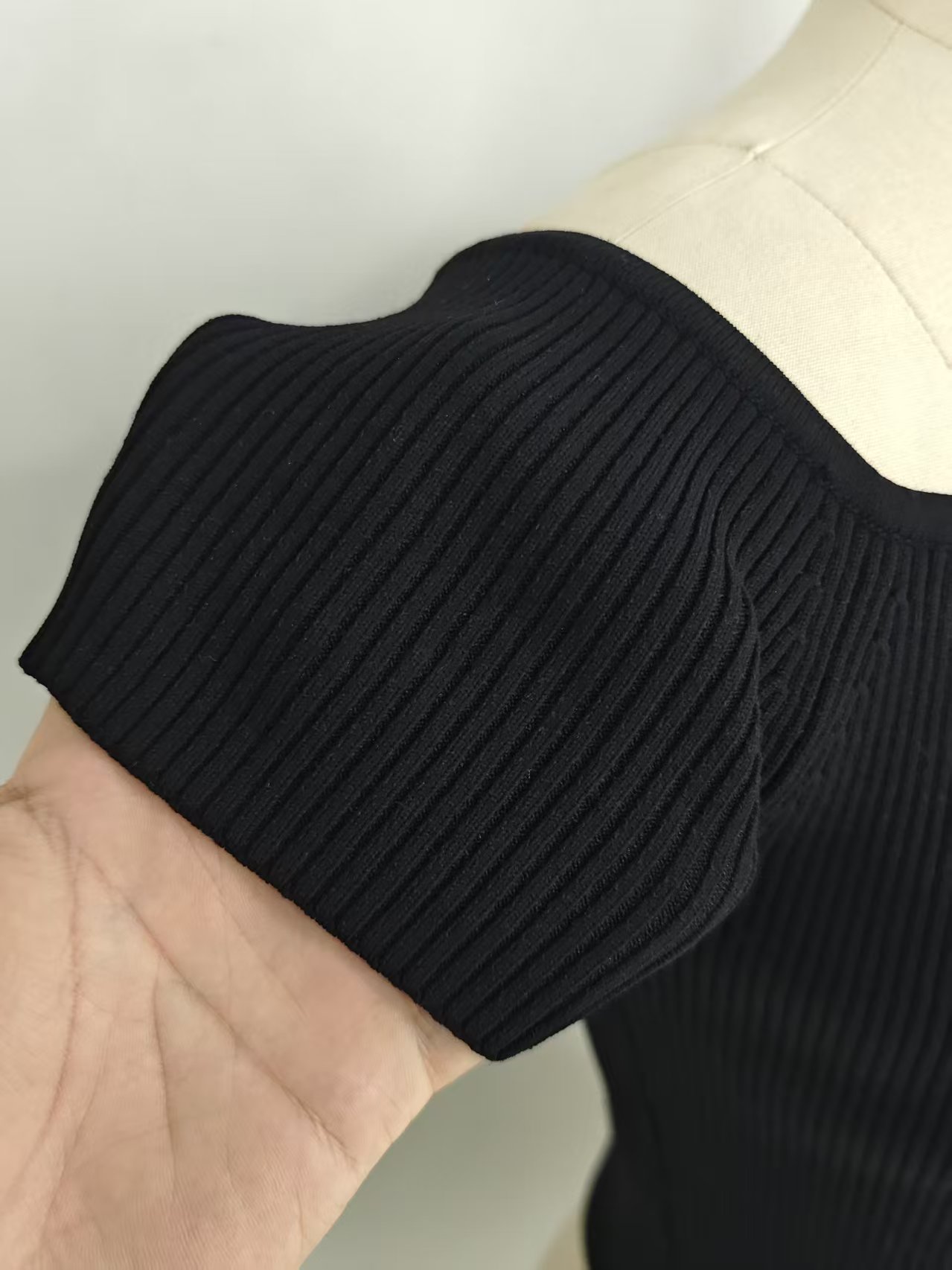 Close-up shot of the black women's ribbed off-the-shoulder crop top on a mannequin.